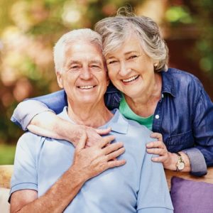older adult couple embracing and smiling for photo in the park